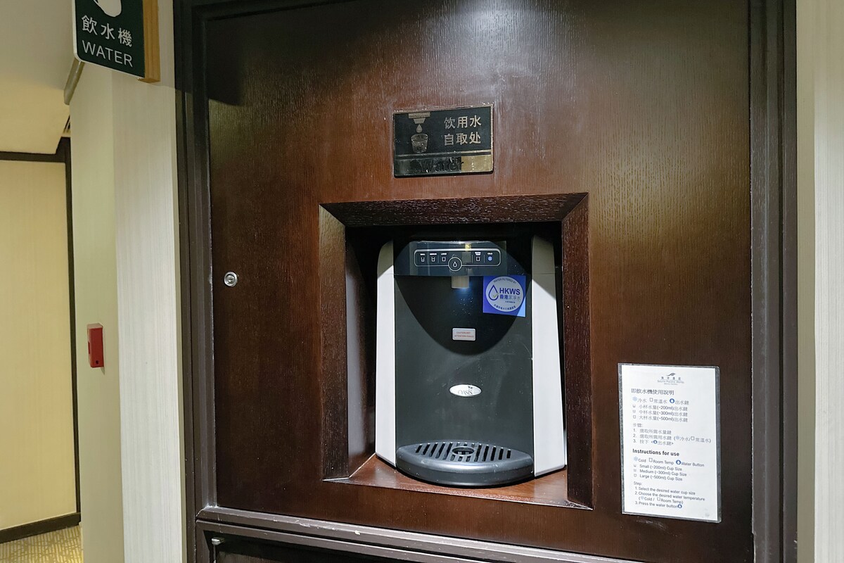 Un dispensador de agua con indicaciones, un cartel que muestra la disponibilidad de agua y un marco de madera.