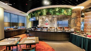 Un restaurante moderno con una barra curva, una pared verde y diversas opciones de platos.