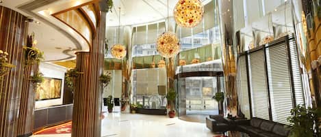 A spacious lobby with high ceilings, large windows, and modern chandeliers.