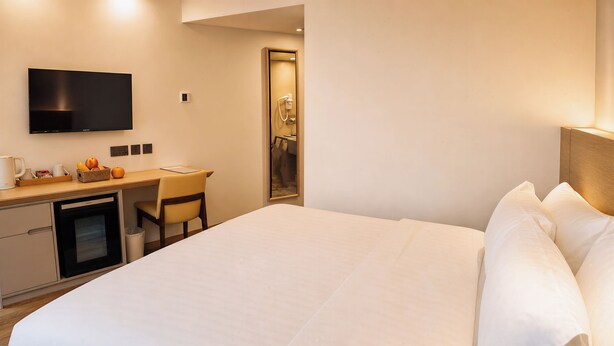 Une chambre d’hôtel équipée d’un lit, d’un bureau, d’une télévision et d’une petite kitchenette.