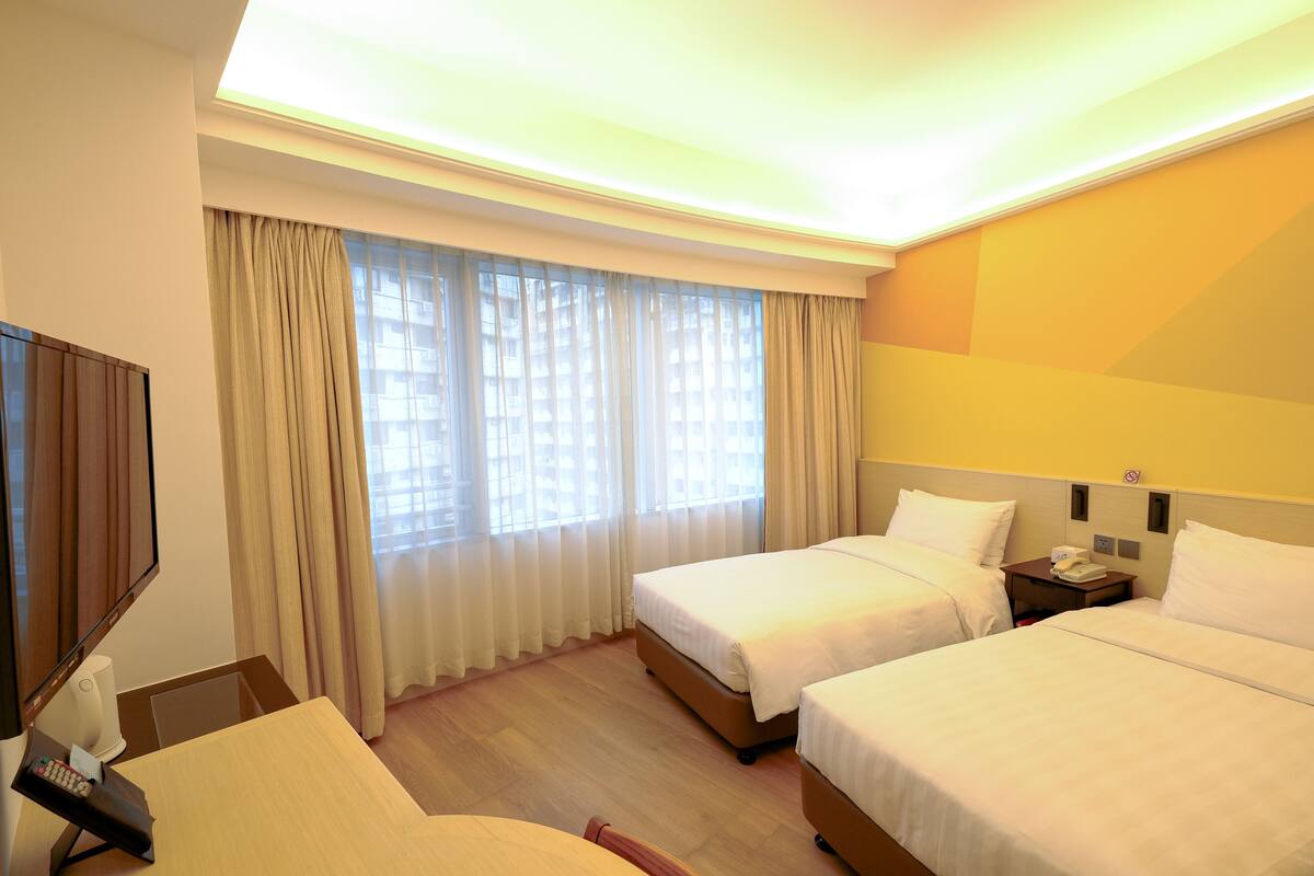 Een hotelkamer met twee bedden, een bureau met telefoon en een televisie.