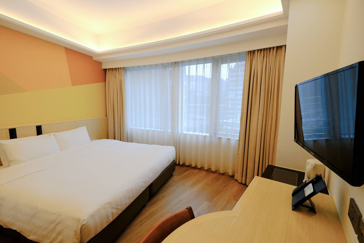 Een hotelkamer met een groot bed, een bureau en een televisie.