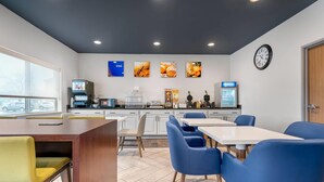 A modern kitchen with a coffee machine, a clock, and framed pictures on the wall. - Comfort Inn & Suites Wisconsin Dells (Wisconsin Dells)