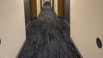 A hotel hallway with a carpeted floor, light-colored walls, and doors on both sides.