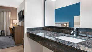 A modern bathroom with a granite countertop, a large mirror, and a sink. - Comfort Inn & Suites Wisconsin Dells (Wisconsin Dells)