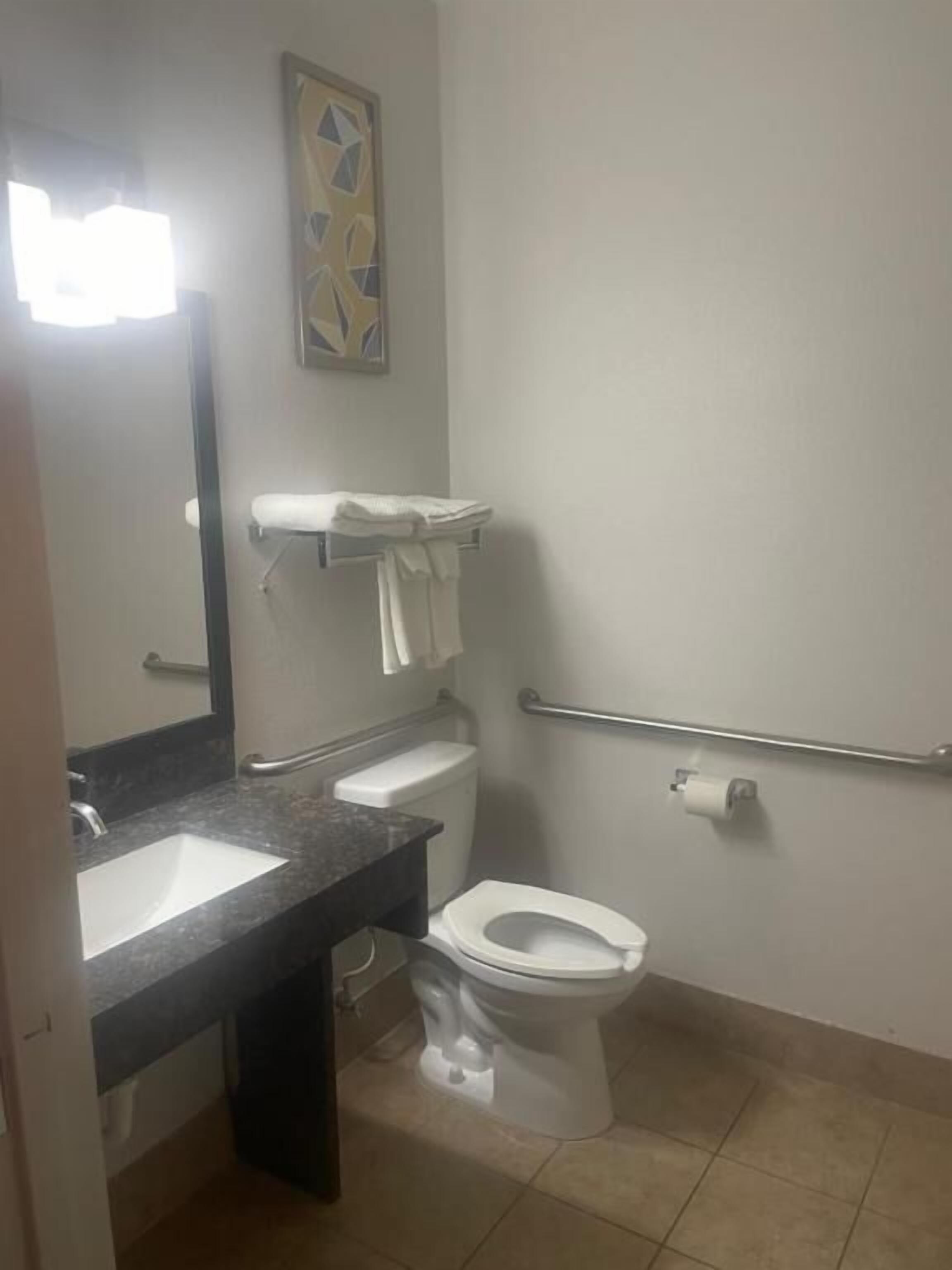 Une salle de bain équipée d’un lavabo, de toilettes et d’une barre d’appui.