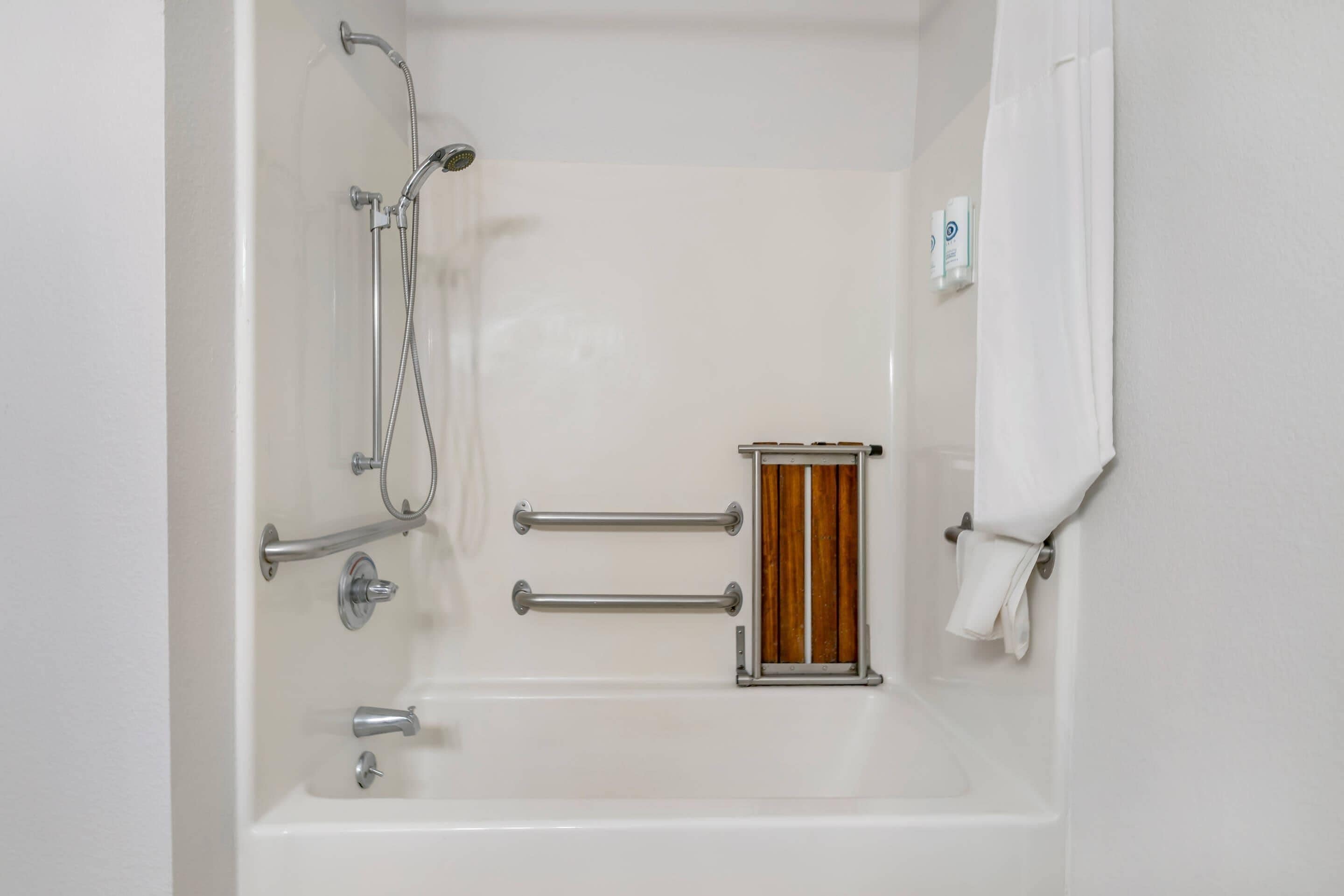 A white bathtub with a showerhead, two towel bars, and a wooden panel.
