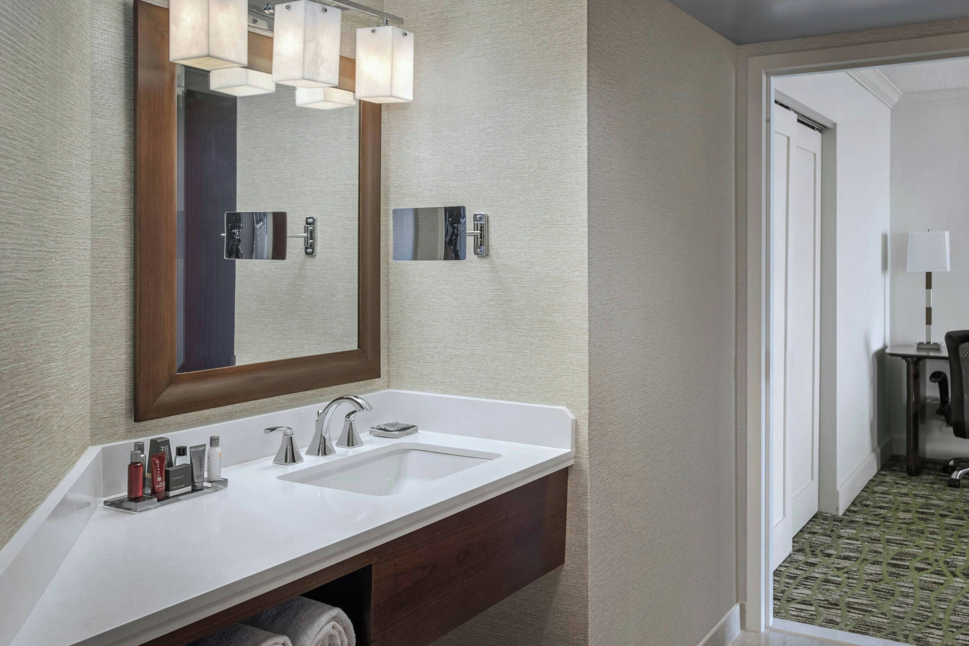 Une salle de bain d’hôtel avec un double lavabo, un grand miroir et un porte-serviettes.