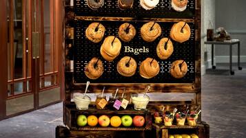 Un carrito de exhibición de alimentos con diversas pastelerías y frutas en el vestíbulo de un hotel.