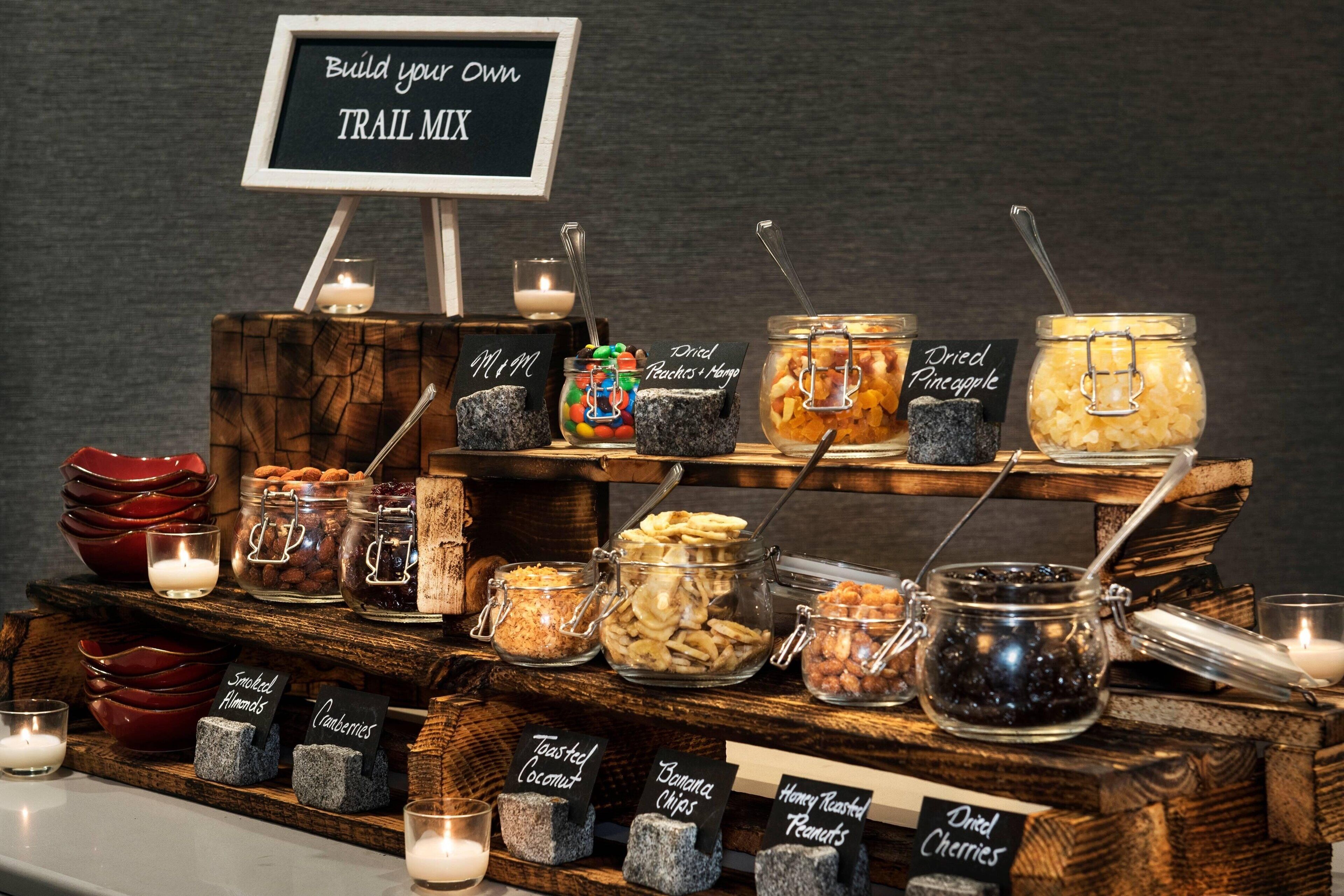 A trail mix station with various nuts, dried fruits, and snacks.