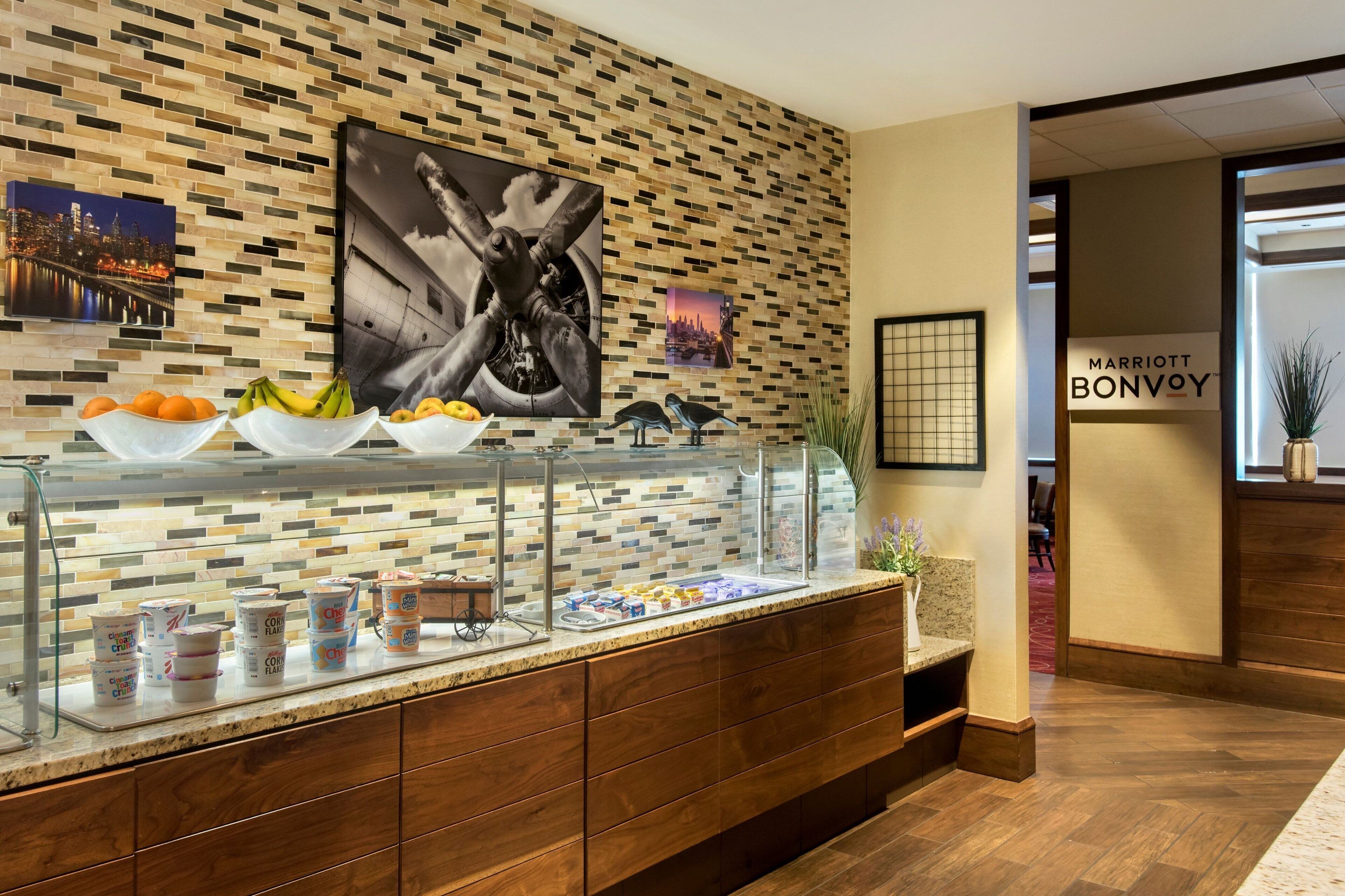 A hotel reception area with a buffet counter, a mosaic wall, and a sign for Marriott Bonvoy.