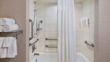 Un baño moderno con ducha, bañera e inodoro. Cuenta con barras de apoyo y un asidero para mayor seguridad.