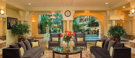 A lobby with a marble floor, two sofas, a coffee table, and a chandelier.