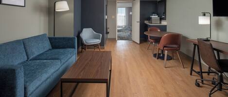 Una sala moderna con un sofá azul, una mesa de centro de madera y una zona de comedor con sillas.