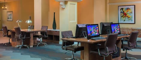 A conference room with multiple desks, chairs, and computer monitors.