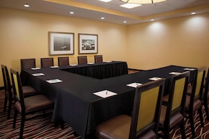 Un salón de conferencias con una larga mesa, sillas y cuadros en la pared.