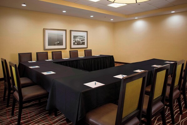 A conference room with a long table, chairs, and framed pictures on the wall.