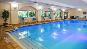An indoor swimming pool with clear blue water, a tiled floor, and a few lounge chairs and tables along the edge. - Four Points by Sheraton Suites Tampa Airport Westshore (Tampa)