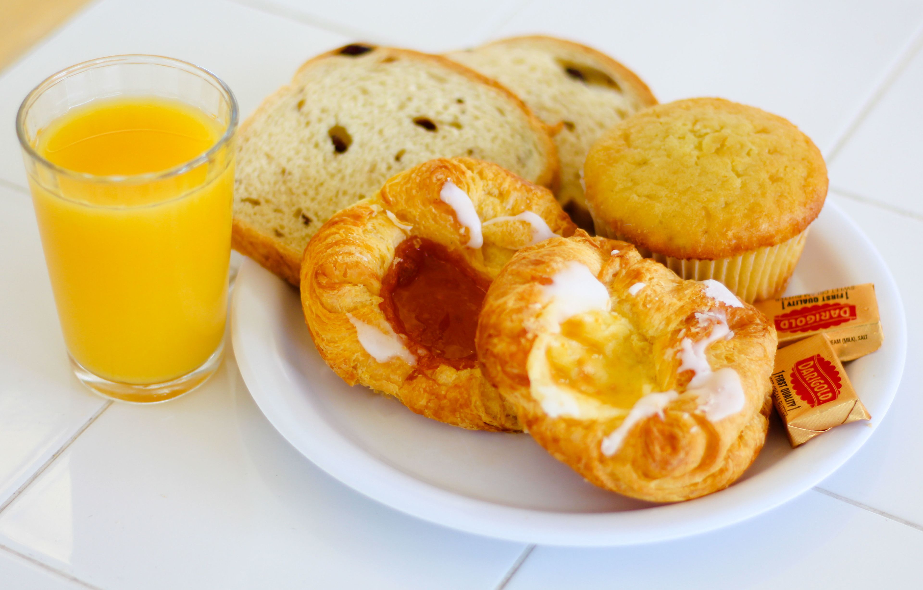 A breakfast plate with croissants, a muffin, and a glass of orange juice.