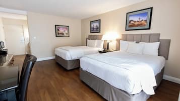 A hotel room with two beds, a desk, and a chair. There are framed pictures on the walls.