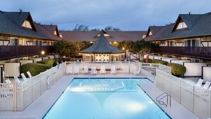 Un área de piscina con sillones de descanso y un pabellón.