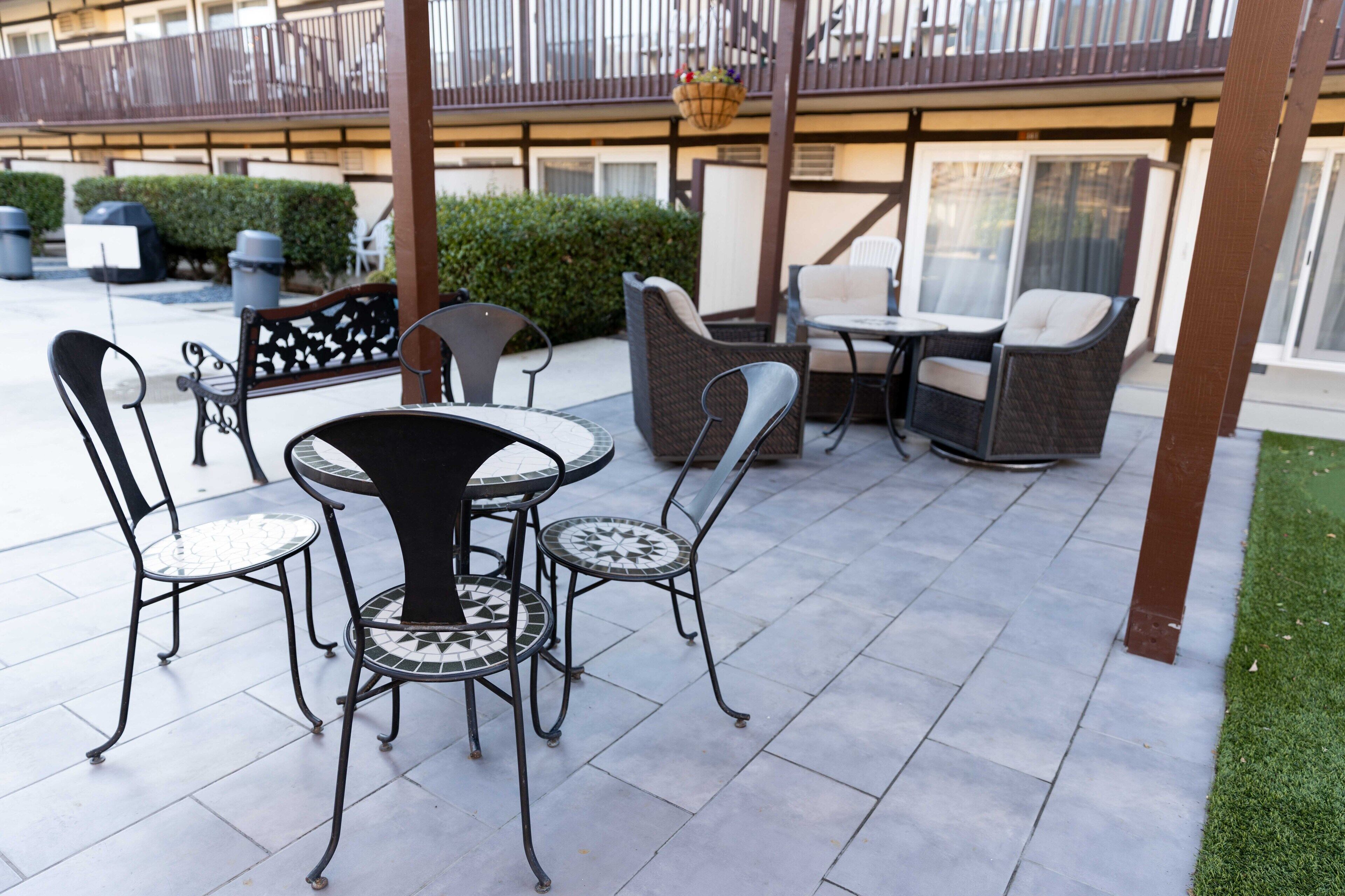 Un patio al aire libre con muebles de mimbre y suelo de baldosas.
