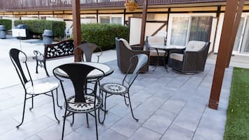 Un patio al aire libre con muebles de mimbre y suelo de baldosas.