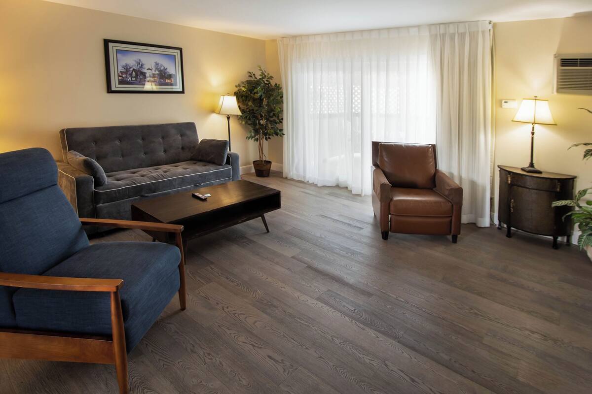 A living room with a sofa, two armchairs, a coffee table, and a potted plant.