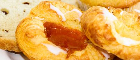 A plate of pastries including a croissant and a muffin with jam and icing.