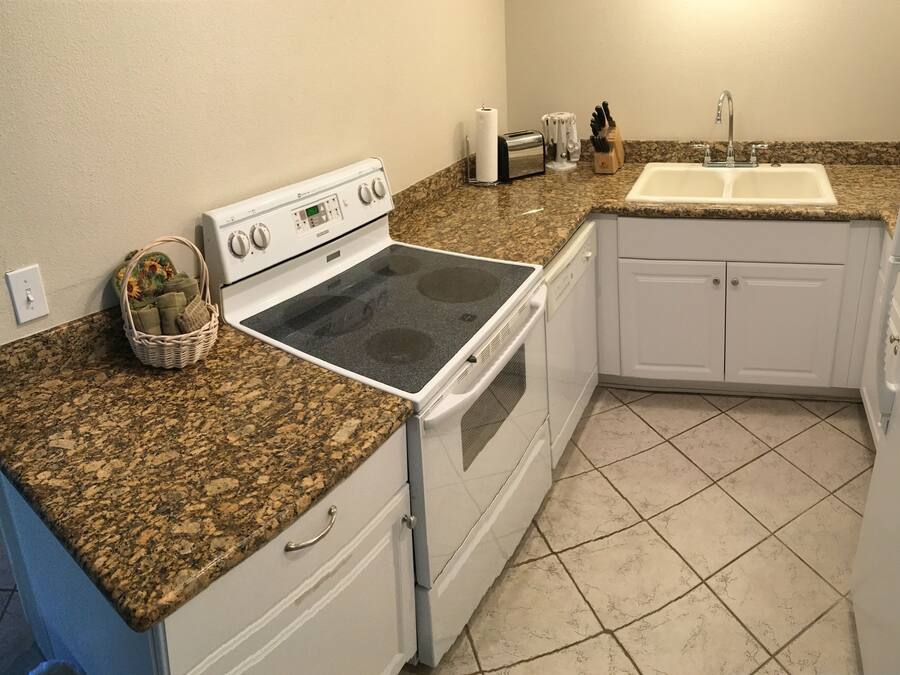 A kitchen with a granite countertop, white cabinets, a built-in oven, and a sink.