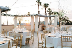 An outdoor dining area with round tables, gold chairs, and string lights.