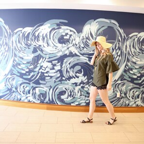 A person walking in front of a large abstract mural. - Redondo Beach Hotel, Tapestry Collection by Hilton (Redondo Beach)