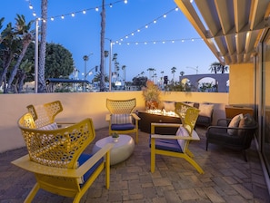 An outdoor seating area with yellow chairs and a fire feature, surrounded by string lights and palm trees. - Redondo Beach Hotel, Tapestry Collection by Hilton (Redondo Beach)