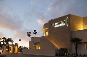 Hotel Redondo Beach con fachada moderna, palmeras y cielo despejado.