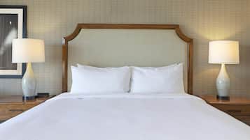 A neatly made bed with white linens, flanked by two bedside tables with lamps, against a textured wall.