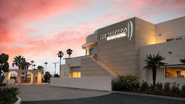 The Redondo Hotel with a modern architectural design, featuring a prominent entrance and a landscaped area with palm trees. - Redondo Beach Hotel, Tapestry Collection by Hilton (Redondo Beach)