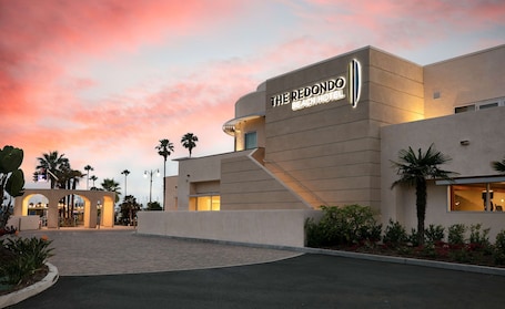 The Redondo Hotel with a modern architectural design, featuring a prominent entrance and a landscaped area with palm trees.