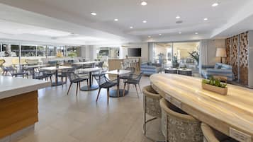 A modern hotel lobby with a bar area, seating arrangements, and a television.