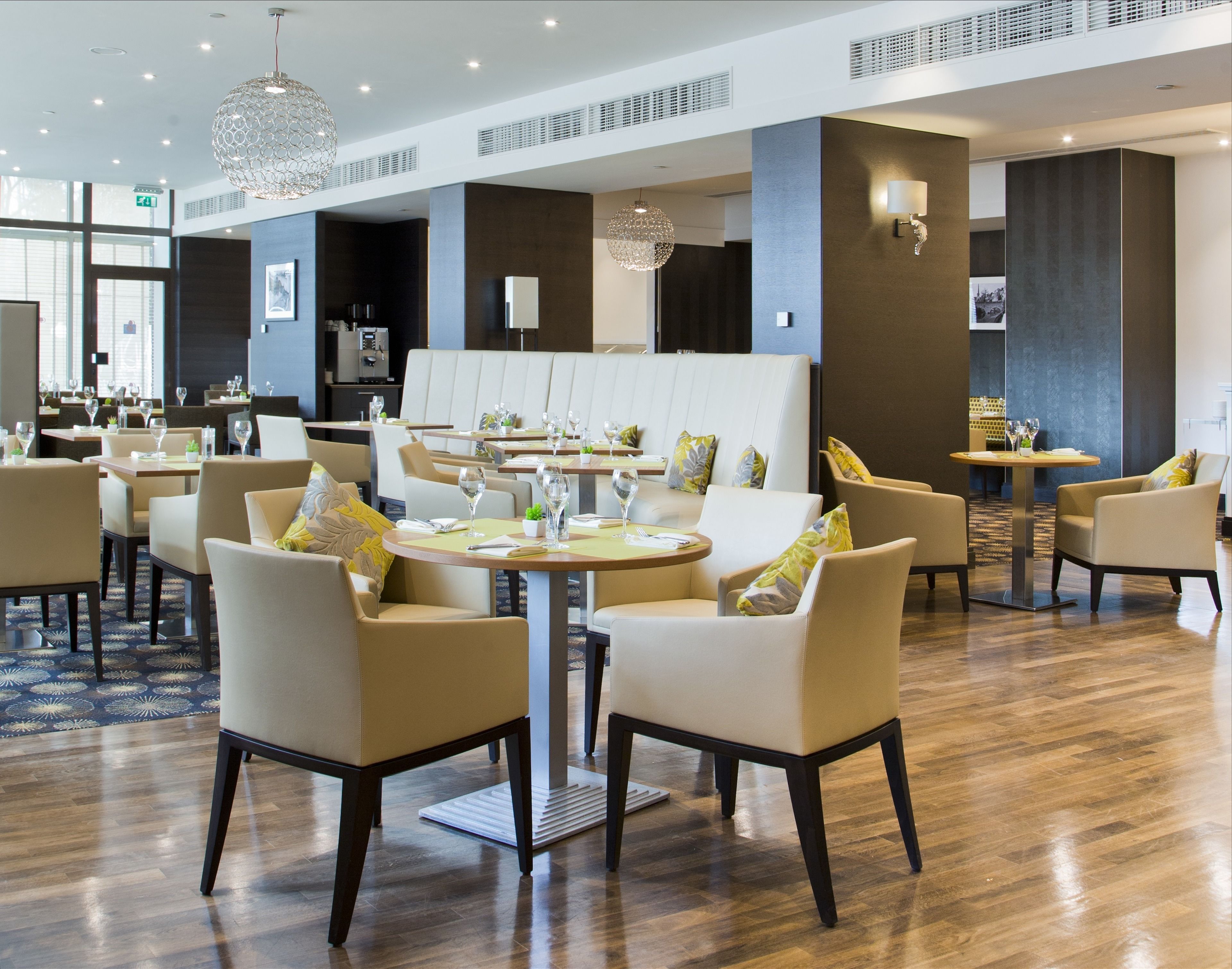 A modern hotel lobby with round tables, comfortable seating, and decorative lighting.