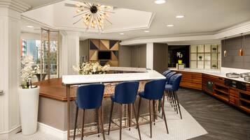 A modern kitchen with a central island, bar stools, and a decorative ceiling light.