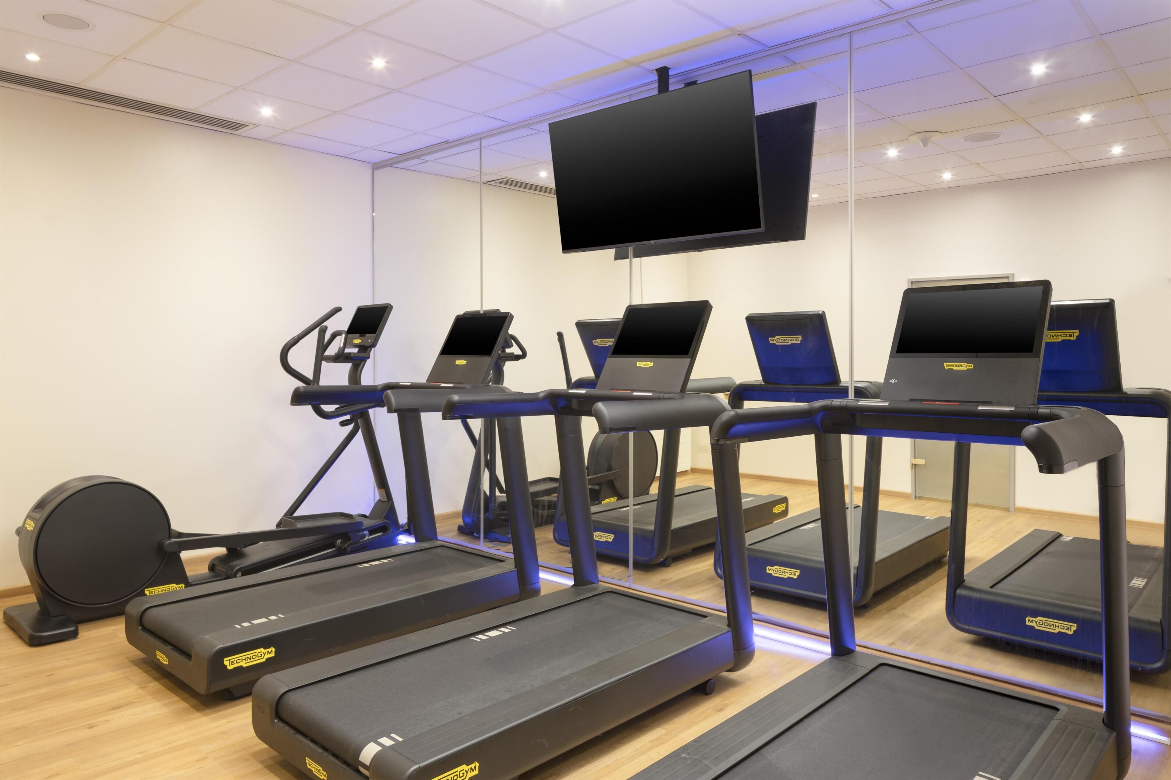A gym with treadmills, elliptical machines, and a stationary bike.