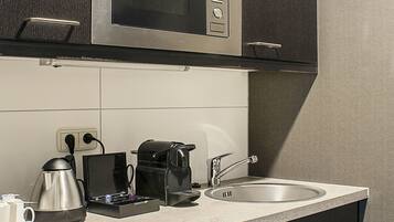 Cozinha moderna com micro-ondas embutido, cafeteira e pia.