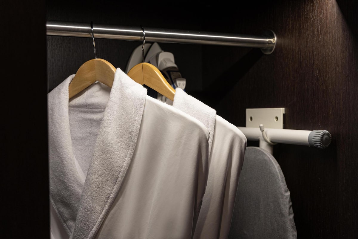 A towel hanging on a metal rod in a dimly lit room with a dark wooden wall.