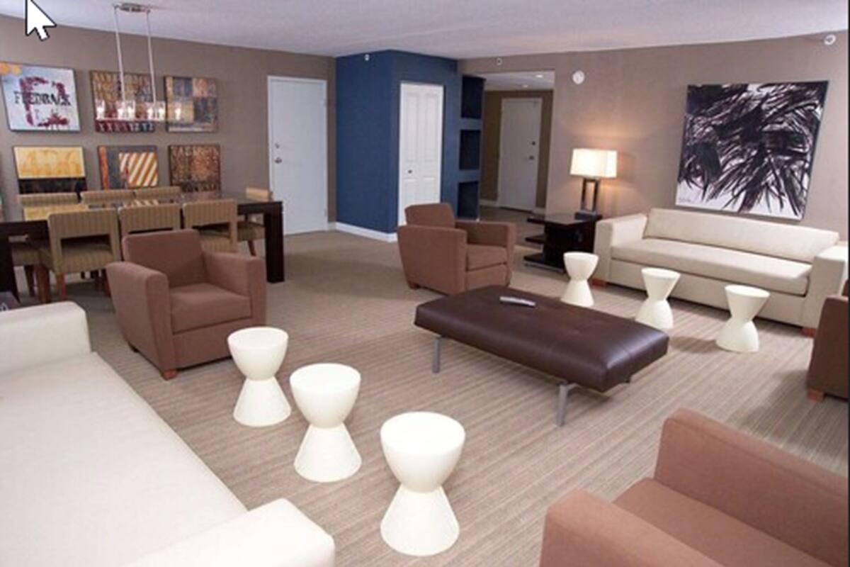 Una sala de estar moderna con un sofá, sillones, una mesa de centro y una zona de TV con escritorio y sillas.