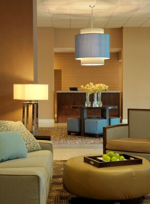 A hotel lobby with a reception desk, seating area, and a large pendant light. - DoubleTree by Hilton St. Louis - Westport (Maryland Heights)