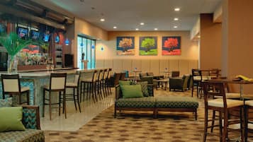 A hotel lobby with a bar area, seating arrangements, and artwork on the walls.