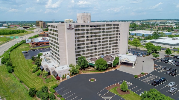 A large, multi-story hotel with a central courtyard and parking area. - DoubleTree by Hilton St. Louis - Westport (Maryland Heights)