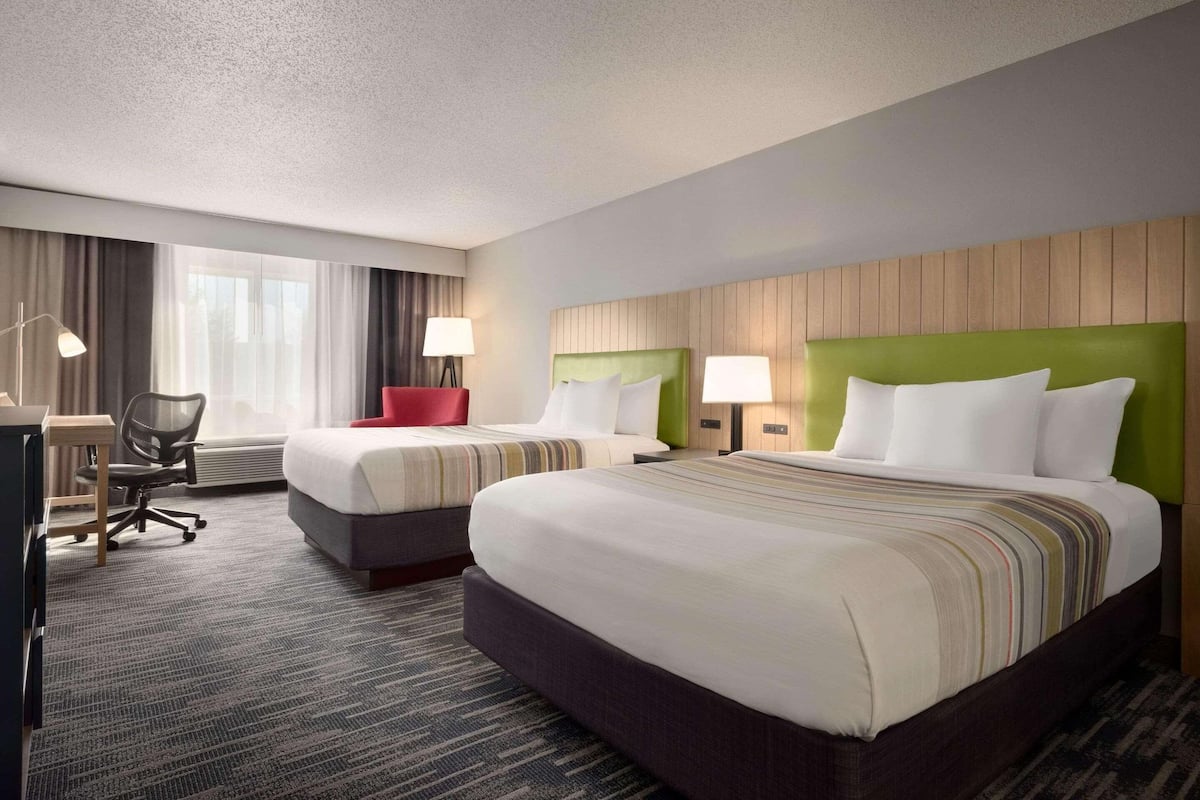 Een hotelkamer met twee bedden, een bureau en een stoel.