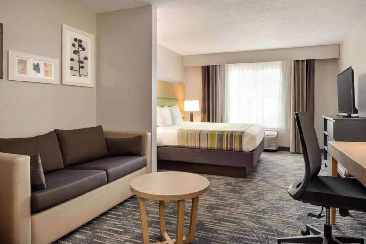 Een hotelkamer met een sofa, een bed, een bureau met een stoel en een televisie.
