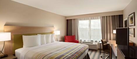 Una habitación de hotel con una cama grande, un escritorio, una silla y un televisor.